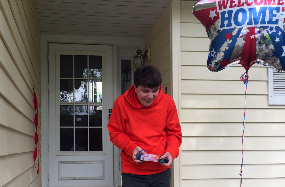 Individual in front of house with welcome home balloon