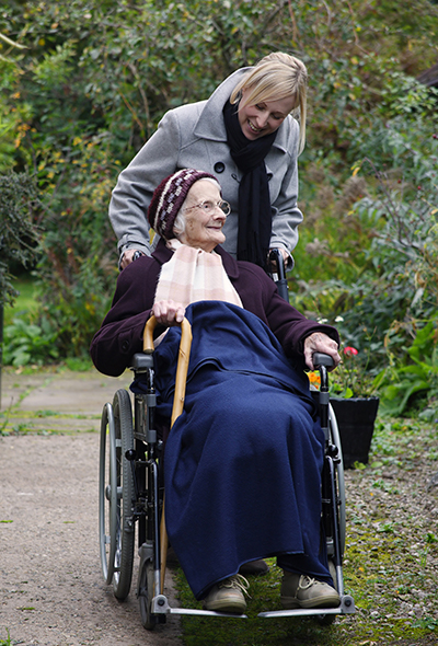 Caregiver and older adult women in a wheelchair outside