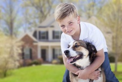 Happy boy with dog in front of house