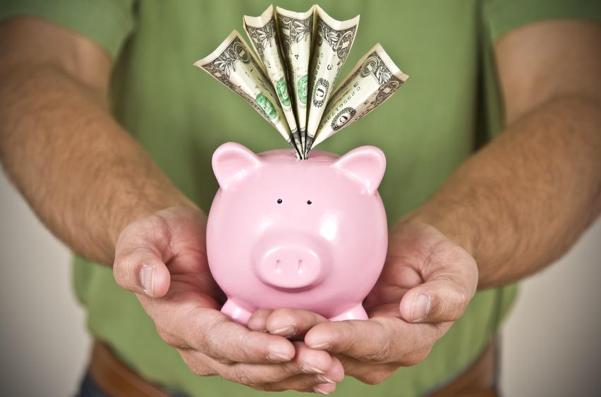 Man's holding a pink piggy bank with bills sticking out of the coin hole
