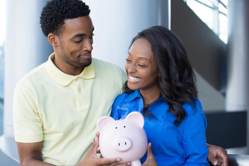Young African-American couple holding piggy bank and smiling