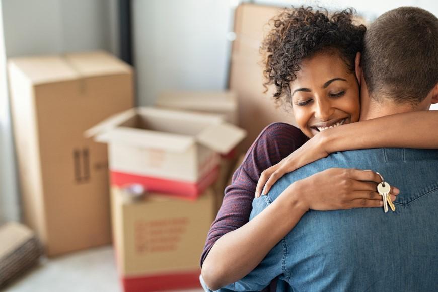 Woman holding keys to new house and hugging partner