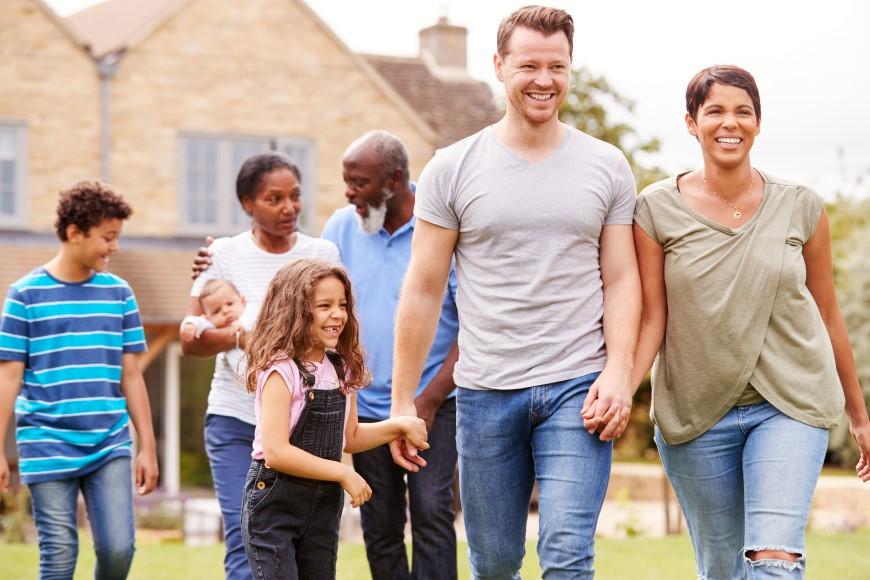 Multiracial and multigenerational family walking together in front of house