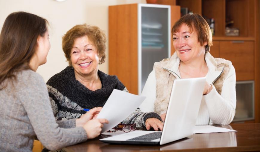 Couple smiling while discussing paper with woman