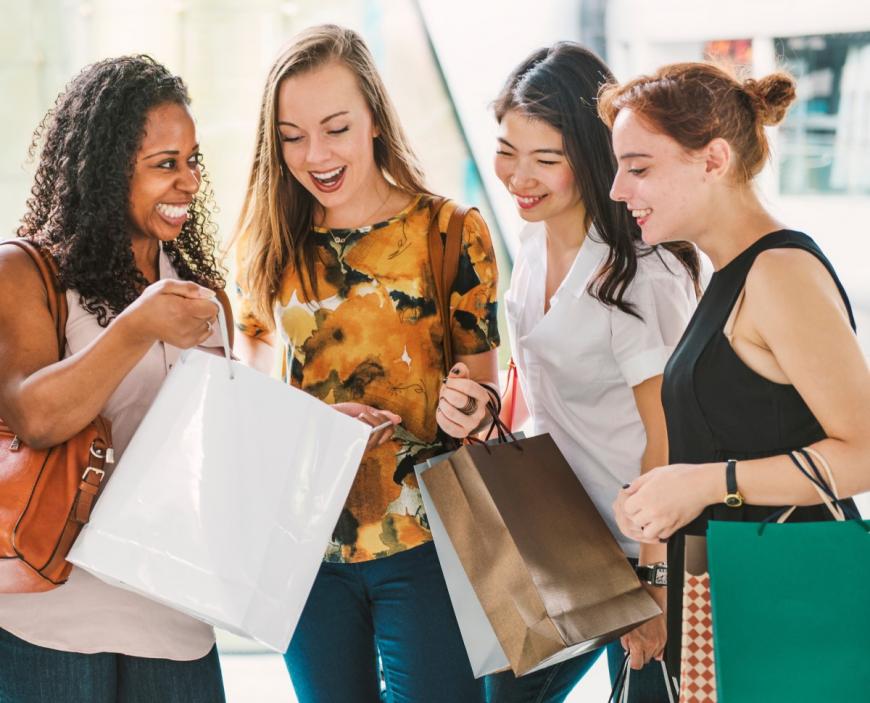 Multiracial group of four women shopping together and lookng at what one of them has purchased