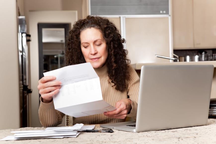 Middle-aged woman at laptop looking at papers