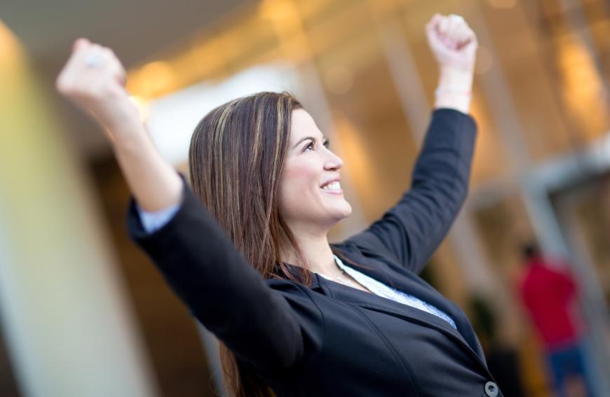 Woman in celebratory pose -- arms raised and fists clienched