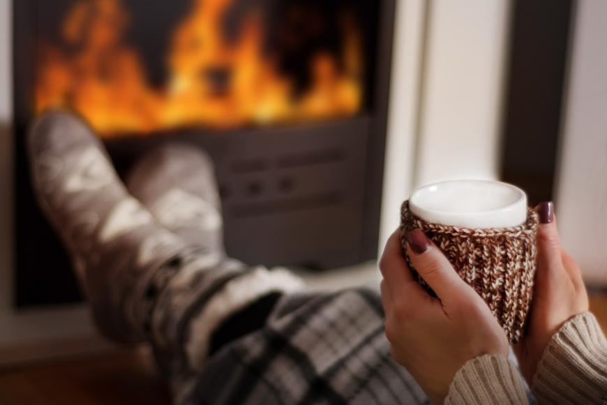 Woman holding hot beverage in front of fireplace