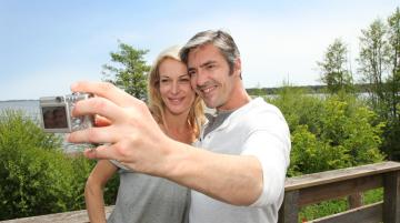 Couple posnig for a selfie next to a wooden fence
