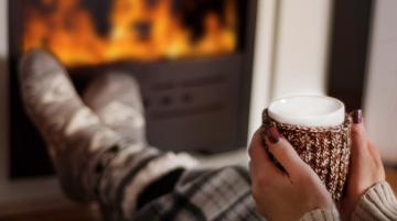 Woman holding hot beverage in front of fireplace