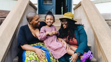 two african american women sitting on steps with their daughter
