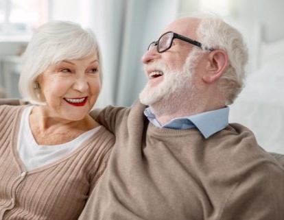 older adults laughing together on a sofa
