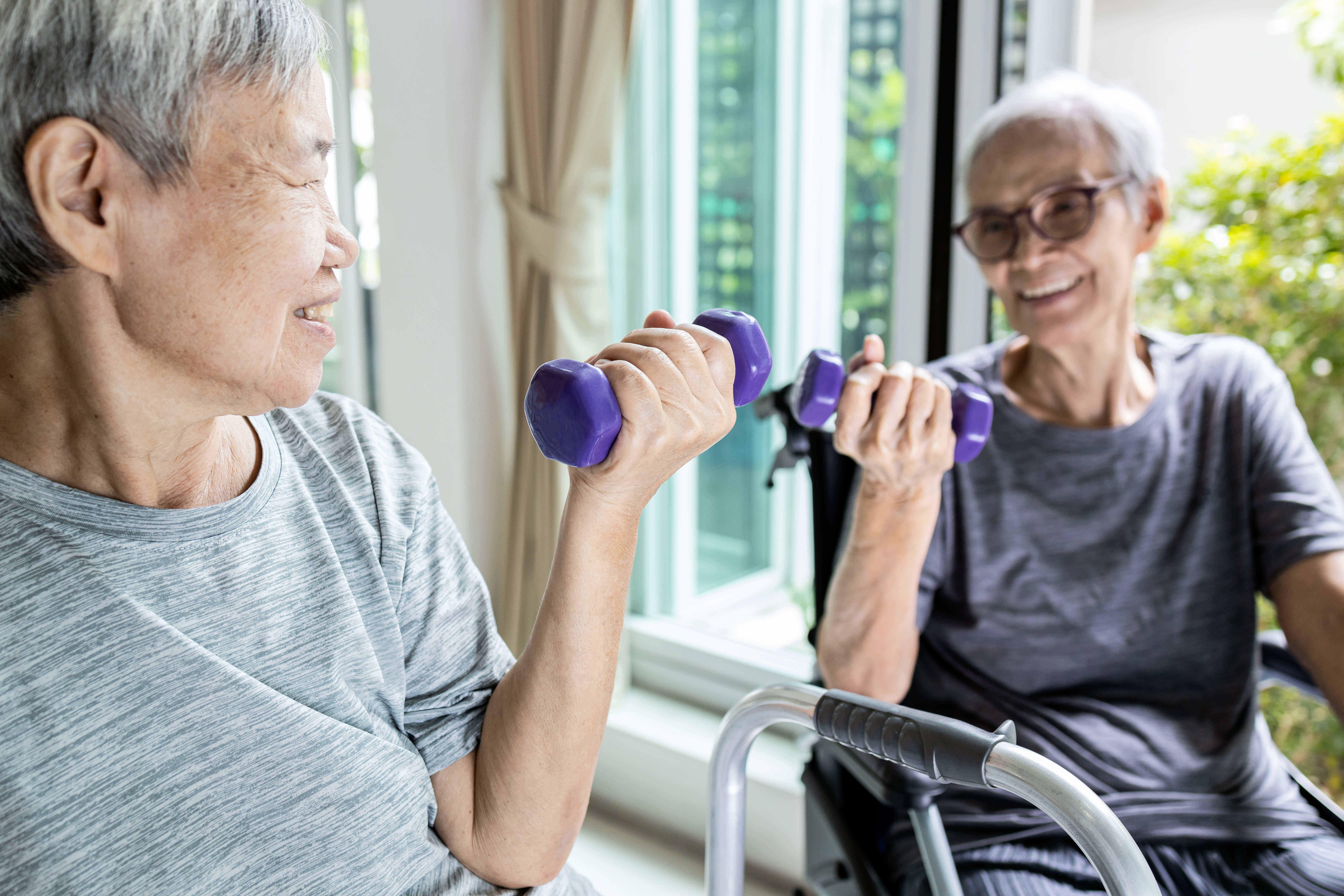 caregiver lifting a weight with older adult woman