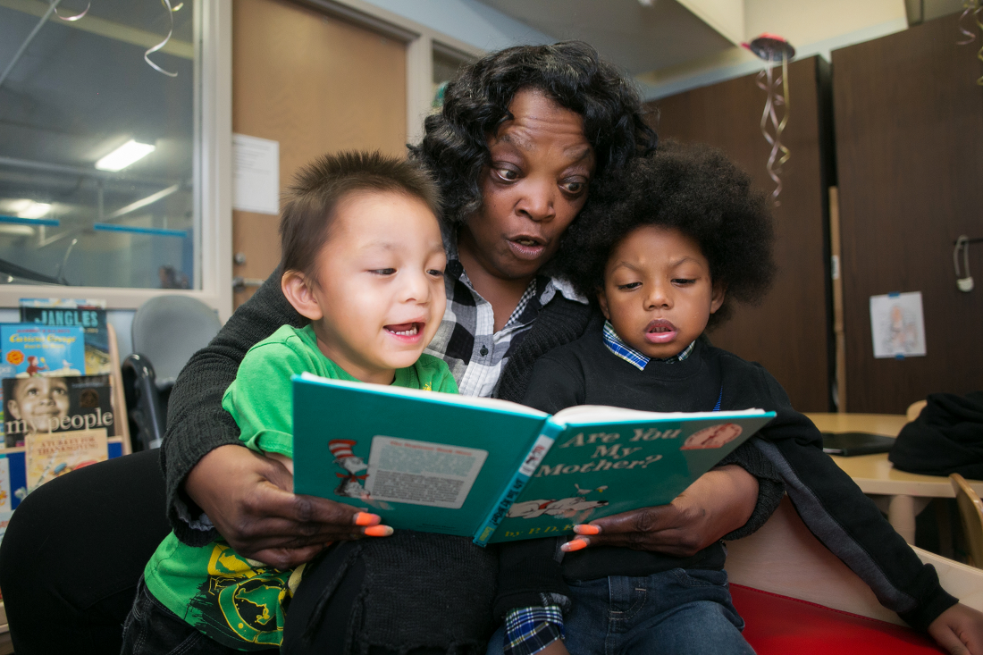 Photo of an LSS Foster Grandparent reading to two children. 