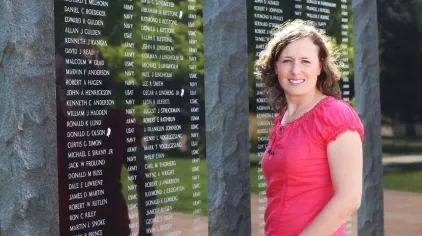 Jolaina standing in front of a memorial wall.