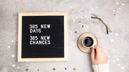 Glasses and coffee cup on a table. Message on a board: 365 New Days. 365 New Chances.