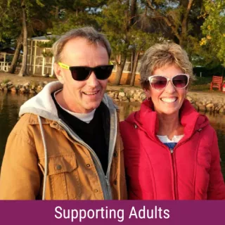 Man and woman wearing sunglasses and smiling. Text reads "Supporting Adults"