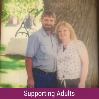 Mark and Lisa Olson with banner that reads "Supporting Adults"